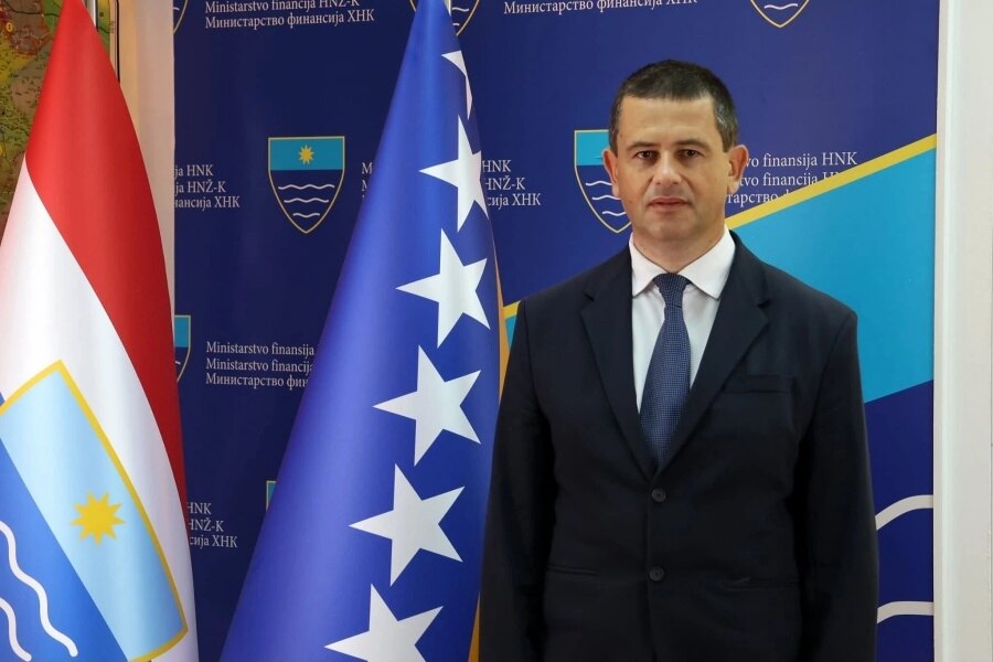 Adil Šuta pored zastave Bosne i Hercegovine, ispred panoa Ministarstva finansija HNK